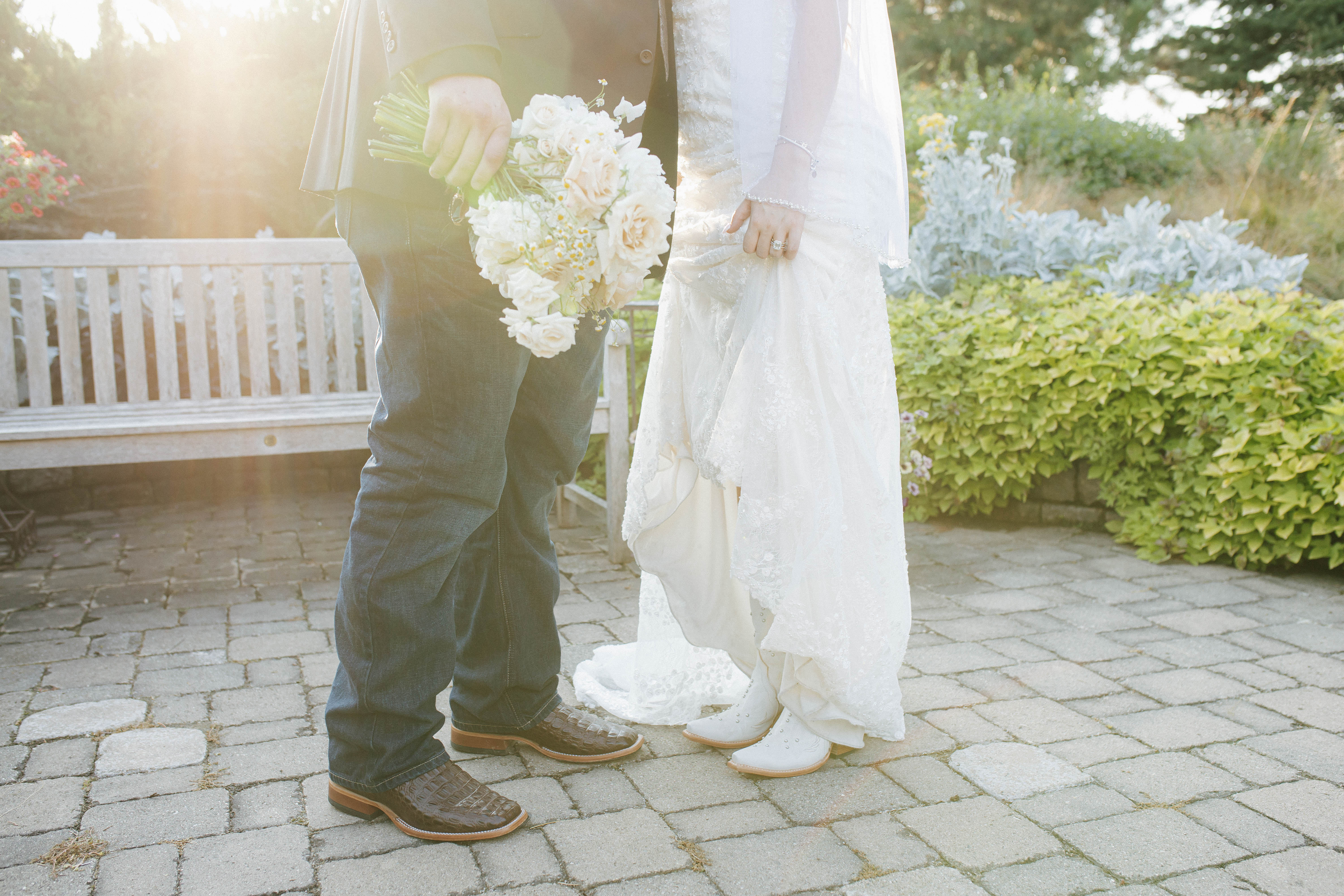 Wisconsin wedding photographer - wedding detail of couple's cowboy boots and white bouquet on garden patio stones